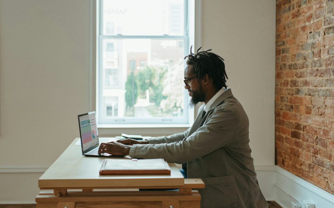 a person sitting at a desk with a laptop and papers